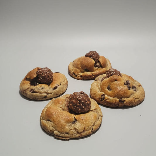 Four cookies with chocolate chips and a truffle on a gray background